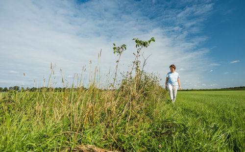 Op deze slide wordt getoond boerin die over agrarisch veld loopt.